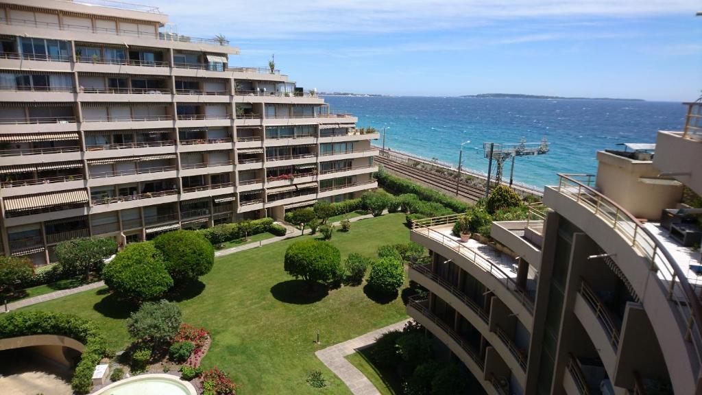 un grand bâtiment avec une pelouse en face de l'océan dans l'établissement Beau studio vue Mer Cannes, à Cannes