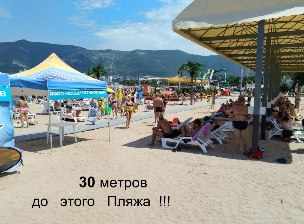 a crowd of people on a beach with umbrellas at 1-линия Апартаменты in Gelendzhik