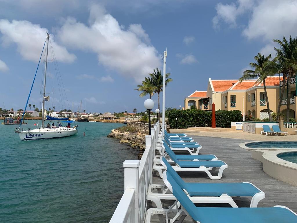 a row of lounge chairs and a boat in the water at Oceanfront Condo with Pool,Breathtaking view, WiFi in Belnem