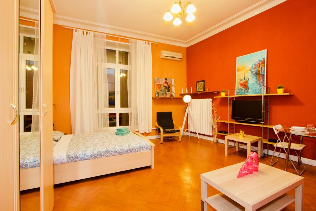1 dormitorio con paredes de color naranja, 1 cama y 1 mesa en KvartiraSvobodna - Apartment at Bolshoy Gnezdnikovskiy, en Moscú