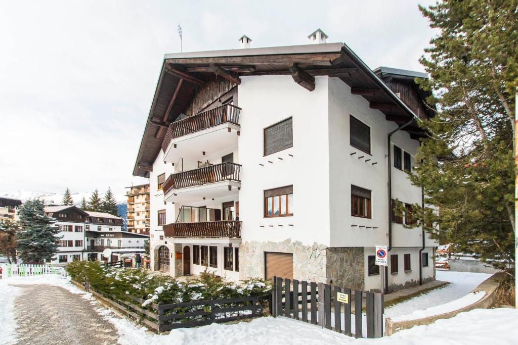 un immeuble d'appartements blanc dans la neige dans l'établissement Appartamento sulla piazzetta centrale, à Sauze dʼOulx