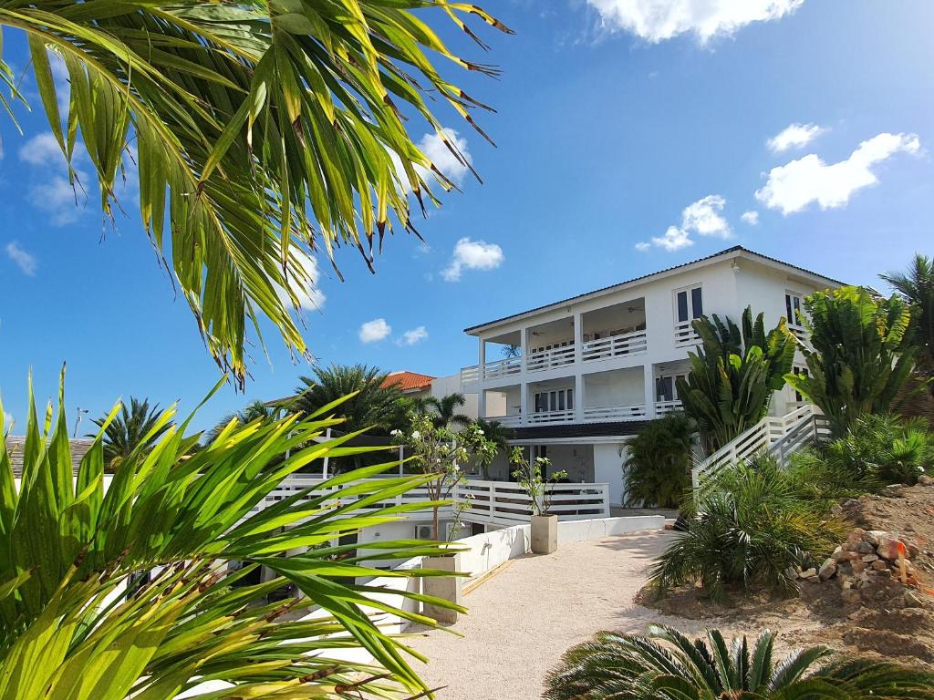 een wit huis aan het strand met palmbomen bij A2 APARTMENT budget at JAN THIEL Curacao in Jan Thiel