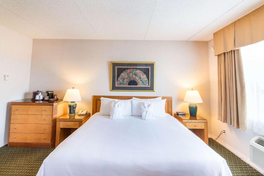 a hotel room with a large bed and two lamps at Ramada by Wyndham Thunder Bay Airlane Hotel in Thunder Bay