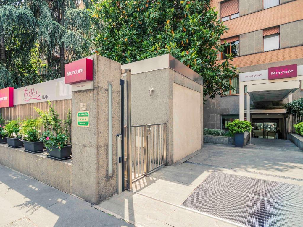 um portão em frente a um edifício com plantas em Hotel Mercure Milano Solari em Milão