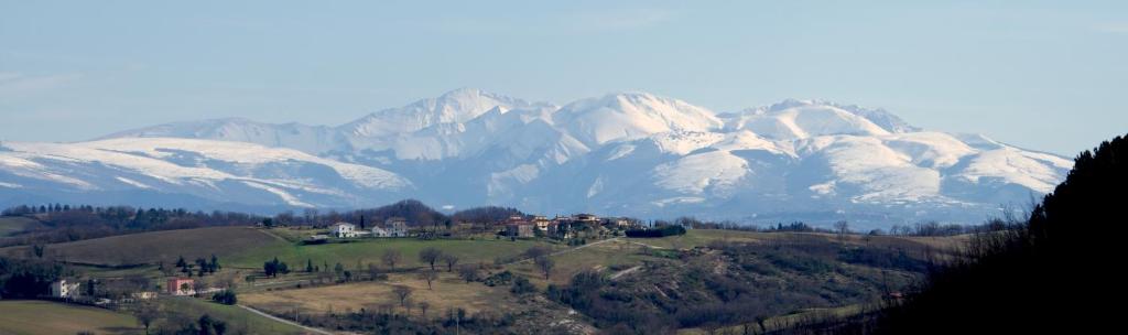 a house on a hill in front of a snow covered mountain at LA FENICE E IL LUPO in Genga