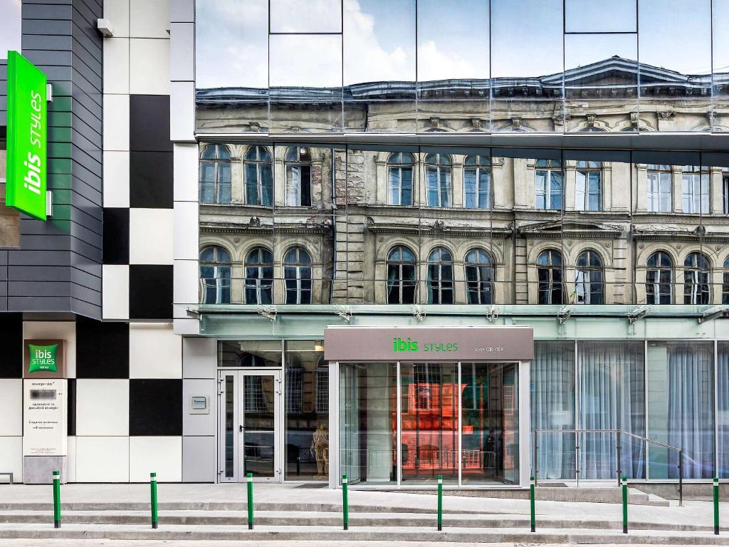 un bâtiment avec un panneau devant lui dans l'établissement Ibis Styles Lviv Center, à Lviv