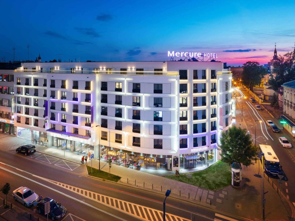 a large white building on a city street at night at Mercure Krakow Stare Miasto in Kraków