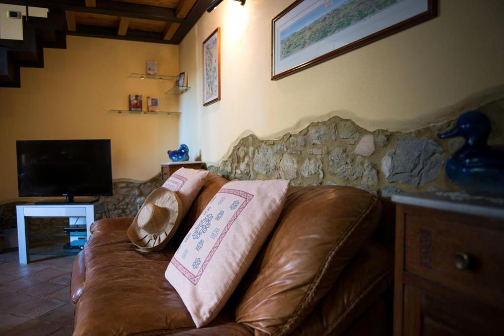 - un canapé en cuir brun dans un salon avec une télévision dans l'établissement Villa La Francigena, à San Gimignano