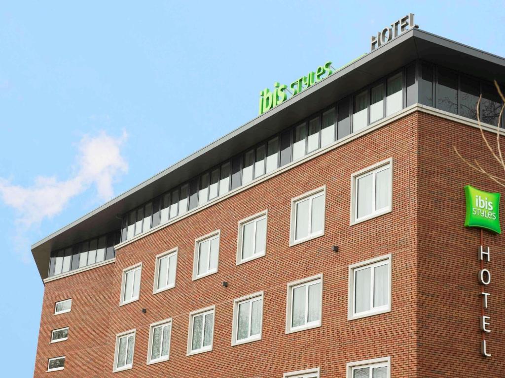 a red brick building with a green sign on it at ibis Styles Haarlem City in Haarlem