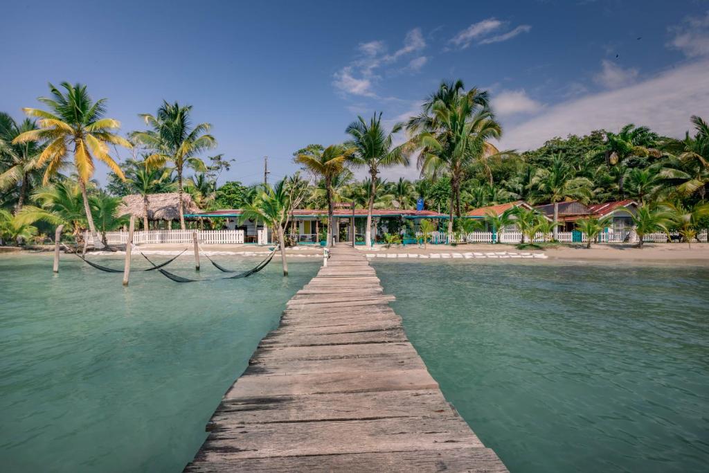 a wooden pathway leading to a beach with palm trees at Doña Mara Gastro Hotel in Bocas del Toro