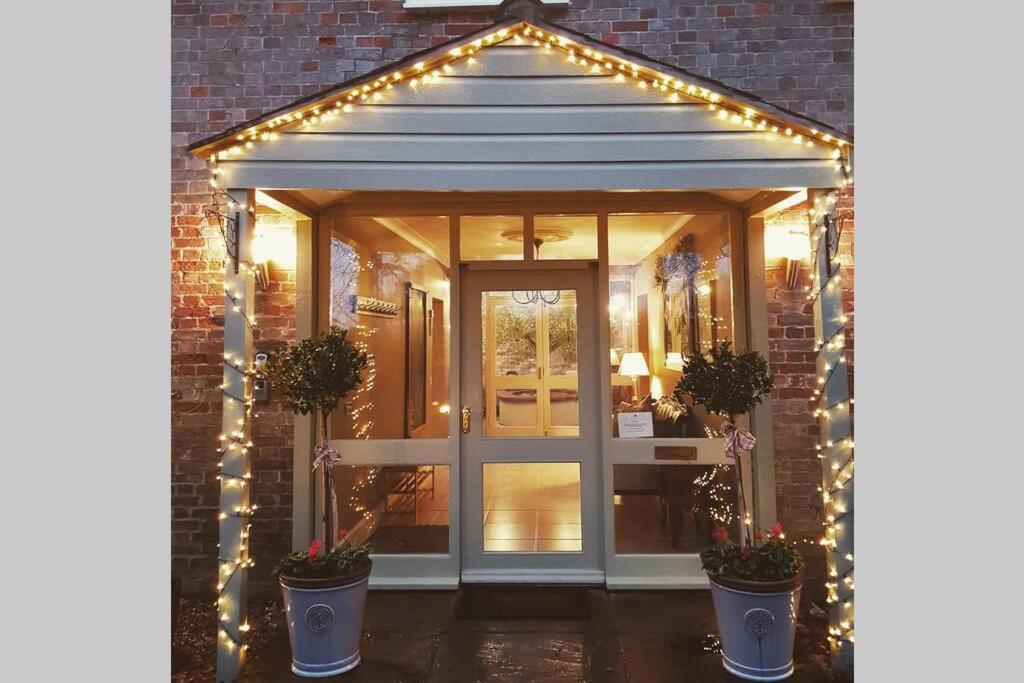 an entrance to a house with lights and a door at The Coach House at Lodge Farm with Hot Tub in Hilgay