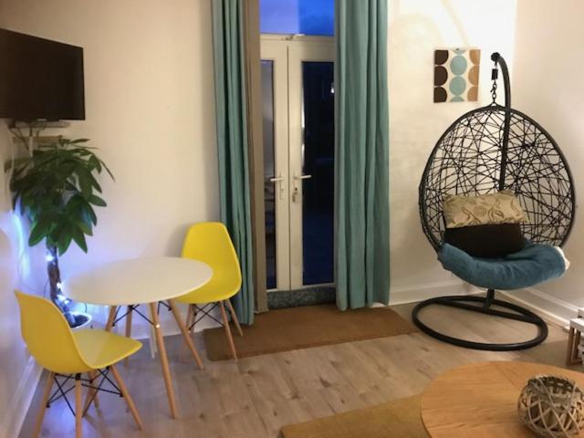 a living room with chairs and a table and a swing at Troon Beachcombers in Troon