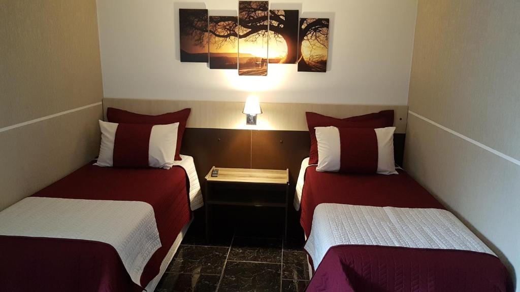 um quarto de hotel com duas camas com lençóis vermelhos e brancos em Hotel Contorno Sul em Curitiba