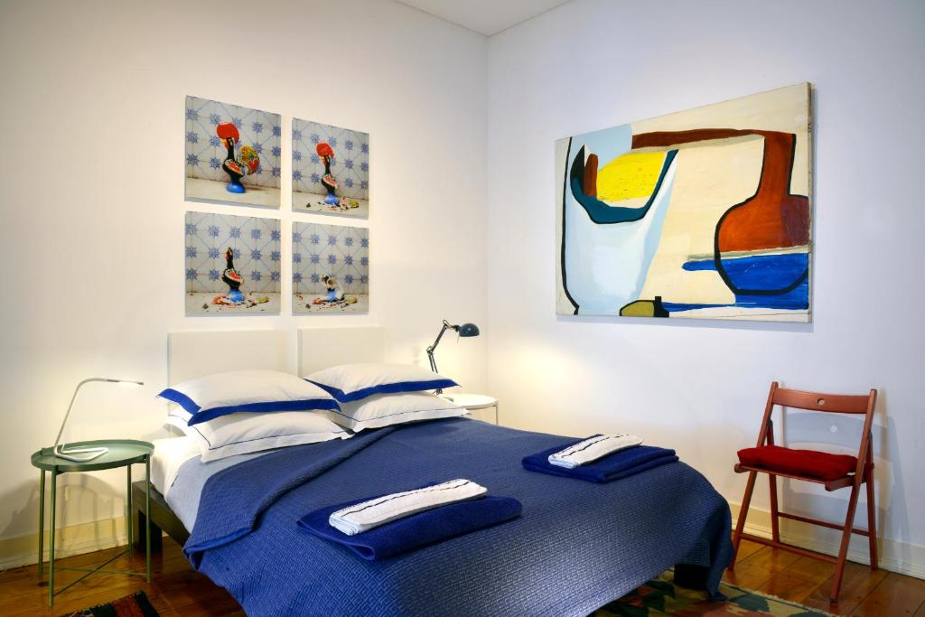 Saldanha Apartment في لشبونة: غرفة نوم بسرير ازرق ولوحات على الحائط