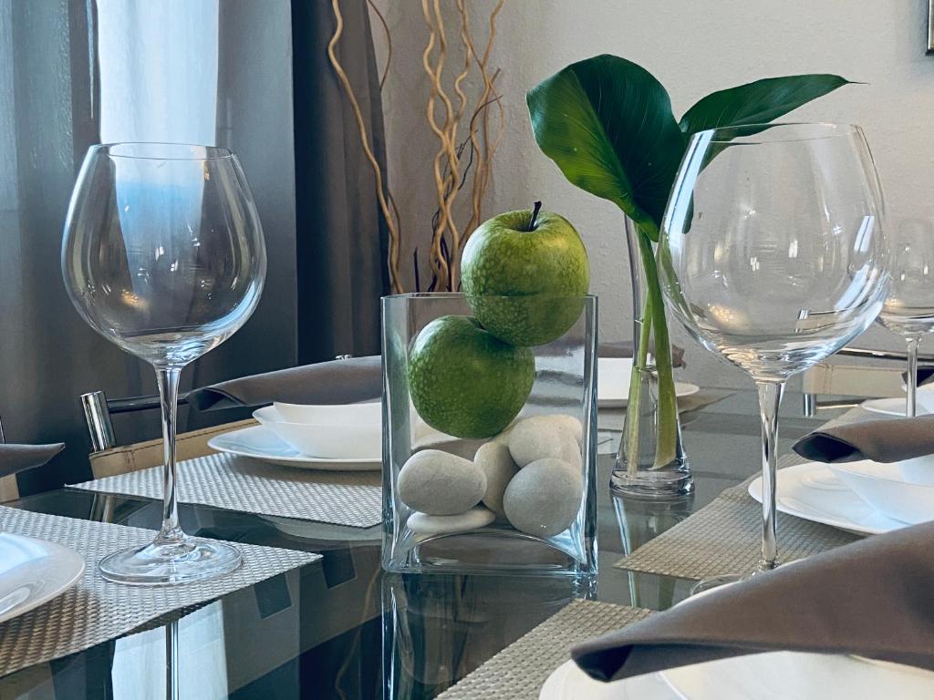 Una mesa con dos vasos y un jarrón con manzanas. en Apartamento Victoria, en Málaga