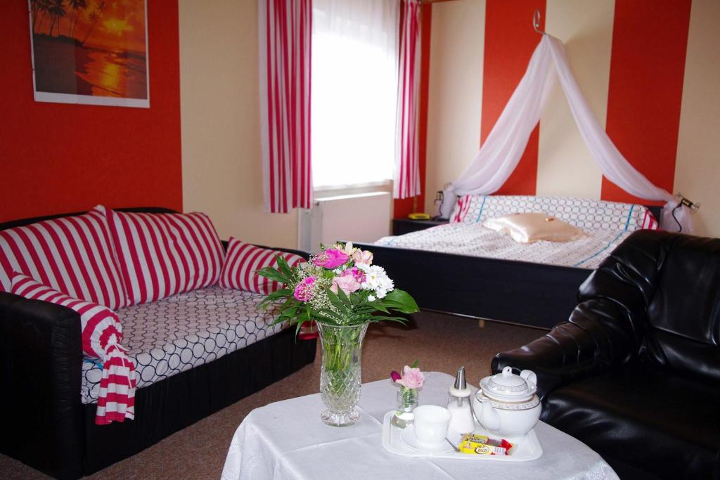 ein Wohnzimmer mit einem Sofa und einem Tisch mit Blumen in der Unterkunft Märkisches Landhaus & Pension Bartsch in Berkenbrück
