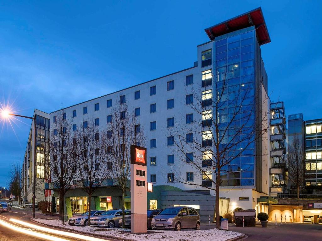 un gran edificio con coches estacionados frente a él en ibis Hotel Stuttgart City en Stuttgart