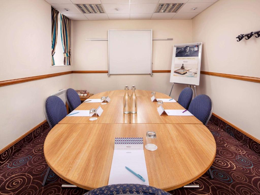 a conference room with a large wooden table and chairs at Mercure Glasgow City Hotel in Glasgow