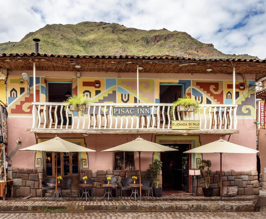 a building with tables and umbrellas in front of it at Pisac Inn in Pisac