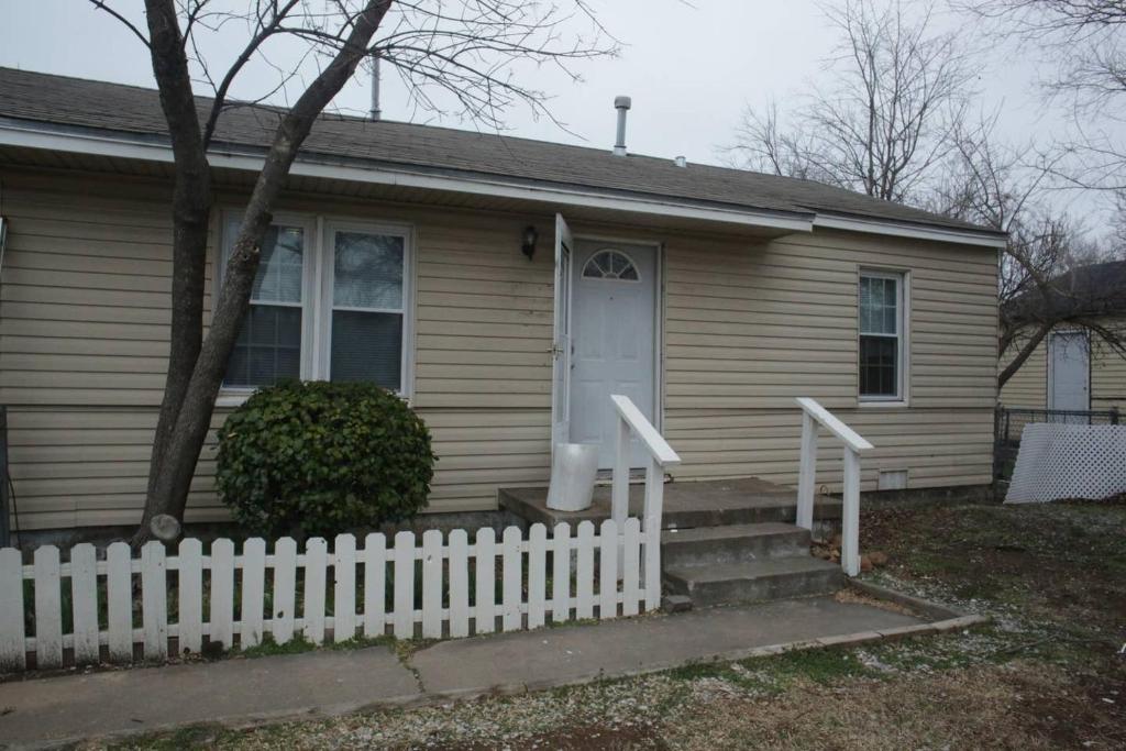 a house with a white fence in front of it at 1 bedroom with a fireplace close to base in Lawton