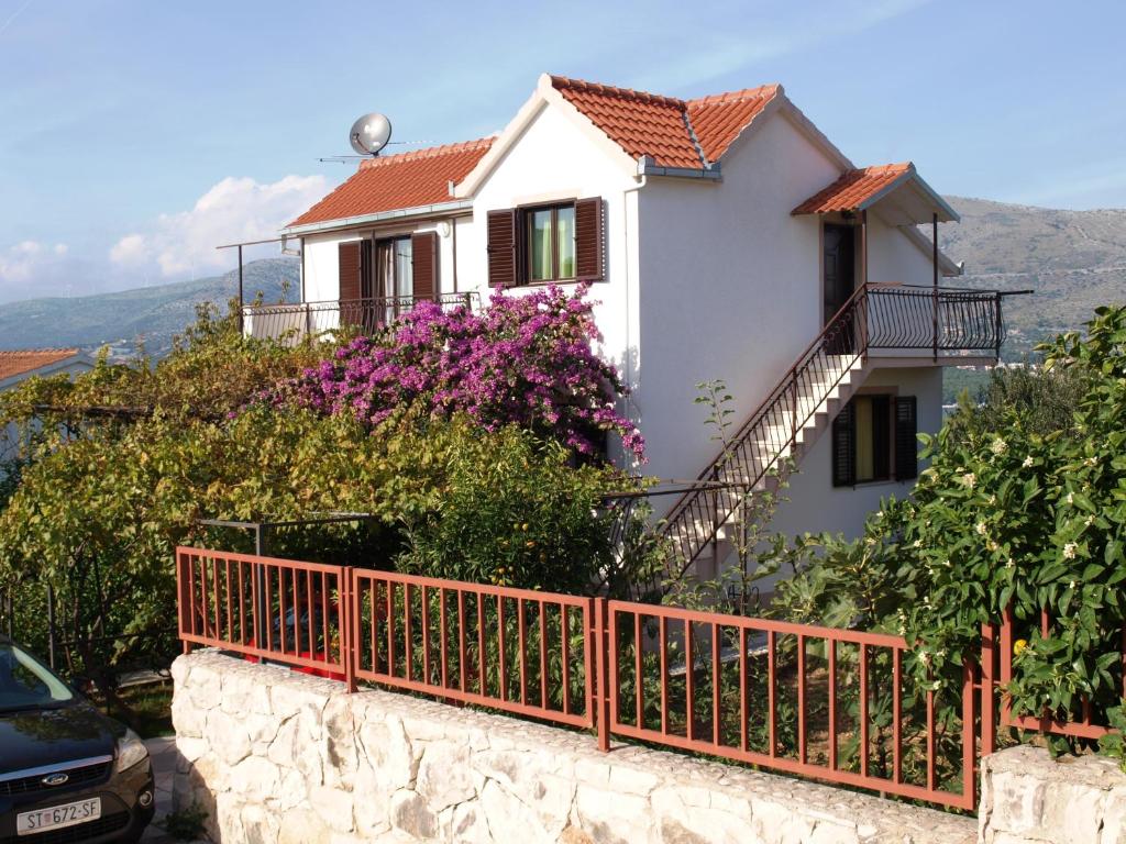 a house on a hill with a fence and flowers at Apartment Zvonar in Okrug Donji