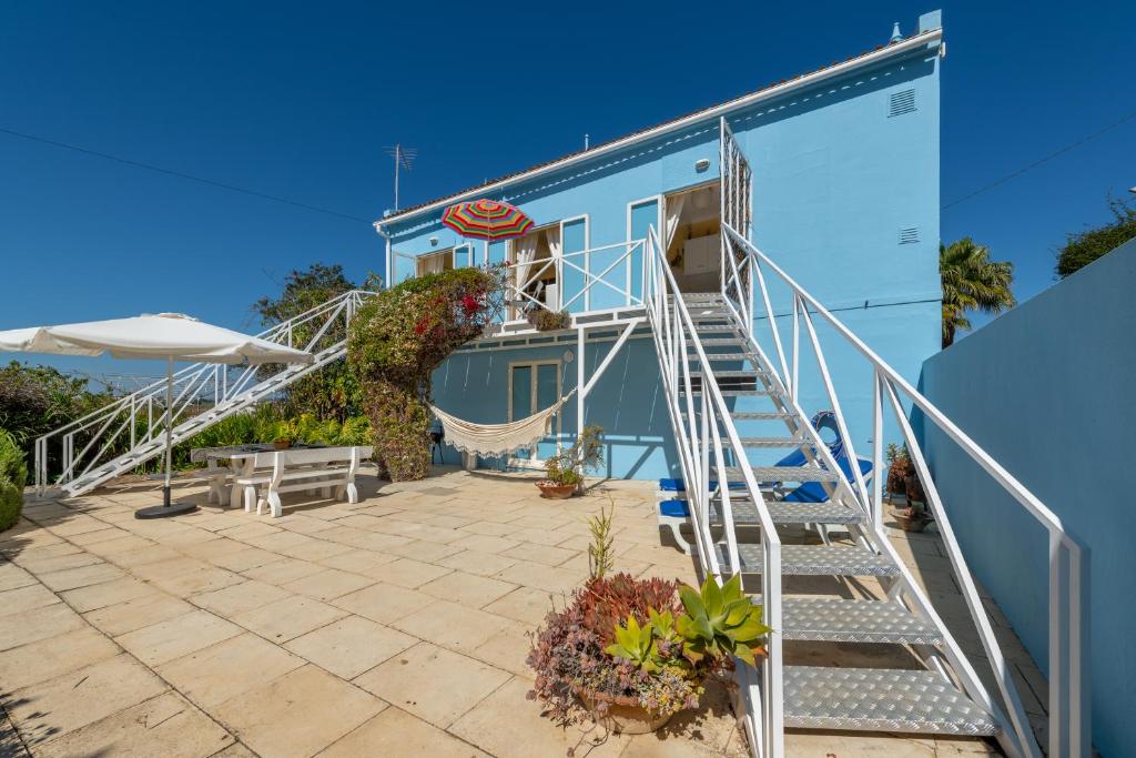 a blue building with stairs and a hammock on a patio at Ceu Azul - Elevated villa with stunning views and big garden in Tavira