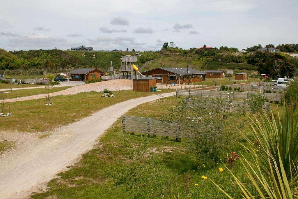 un camino de tierra que conduce a una granja con casas en Hokitika Holiday Park, en Hokitika