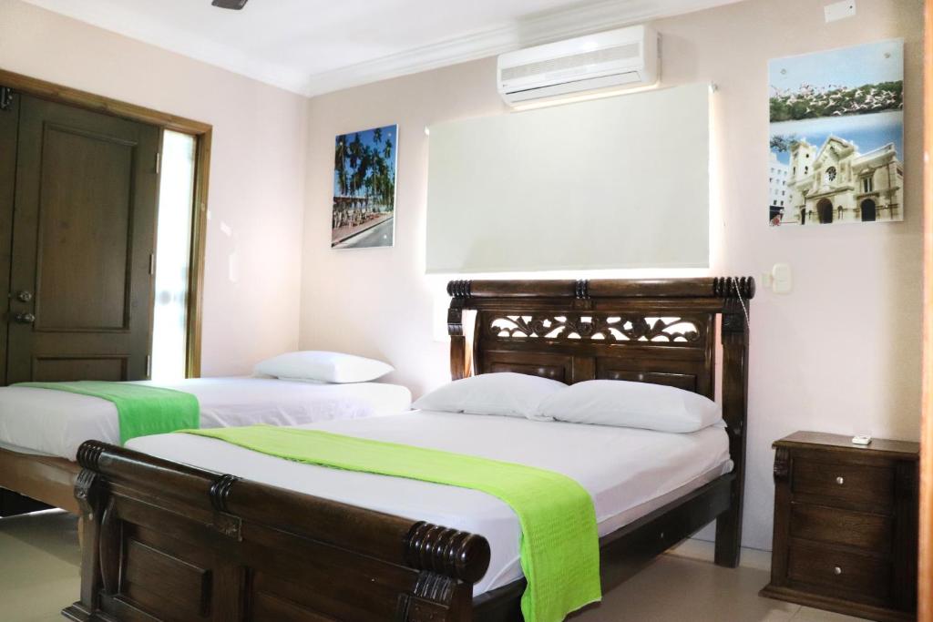 a bedroom with two beds with green blankets at Hostal Santa Cecilia in Ríohacha