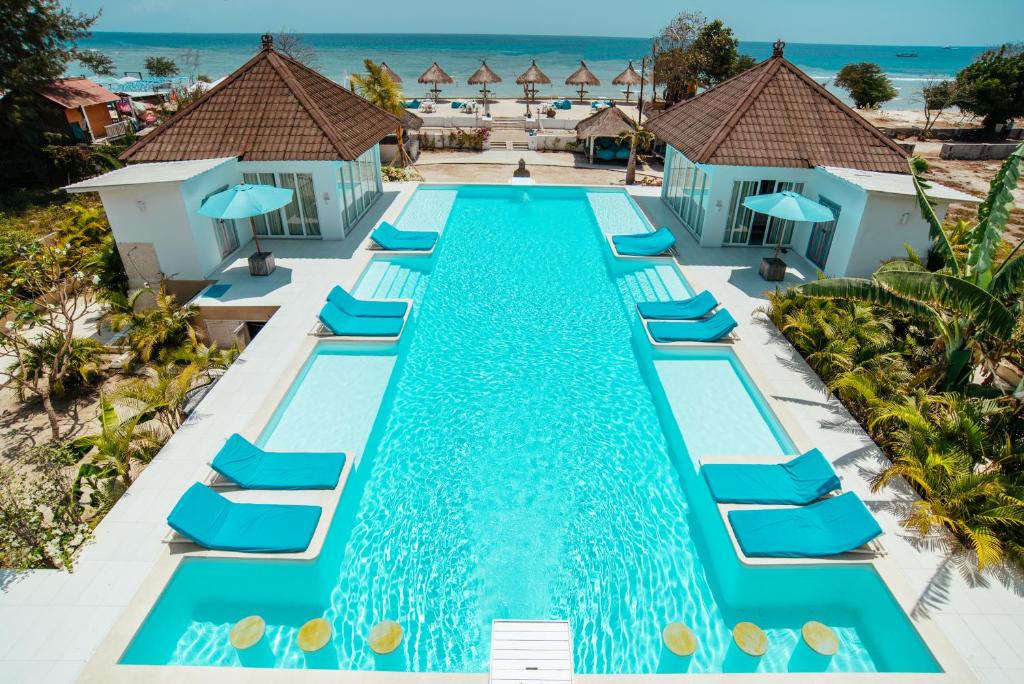 vista aerea su una piscina con sedie a sdraio blu e sull'oceano di Villa Gili Bali Beach a Gili Trawangan