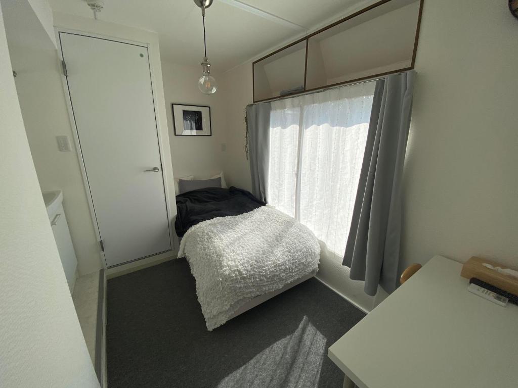 a small bedroom with a bed and a window at CASA KUNISAKU in Machida