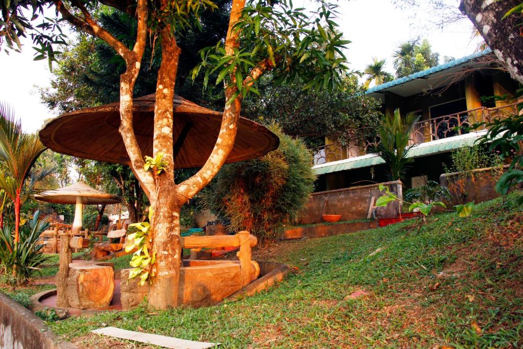 a tree with a bench in front of a building at Elephant Pass Ayurveda & Yoga Retreat in Malayāttūr