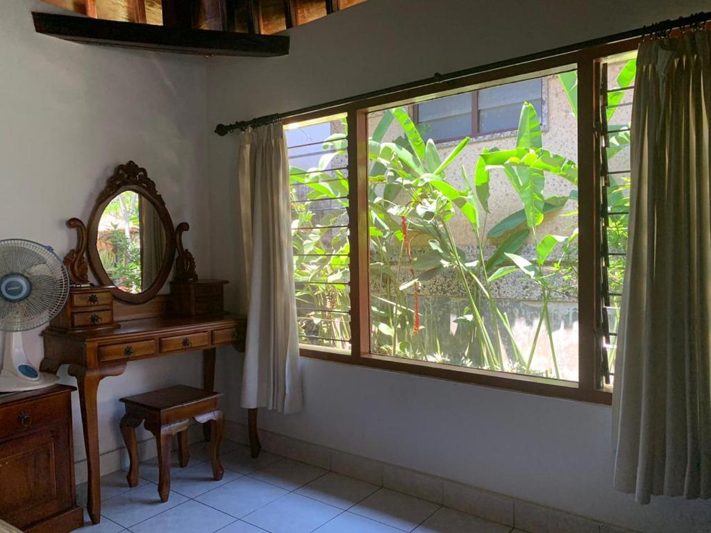 Zimmer mit einem Fenster, einem Schreibtisch und einem Spiegel in der Unterkunft Mandala Bungalows in Ubud