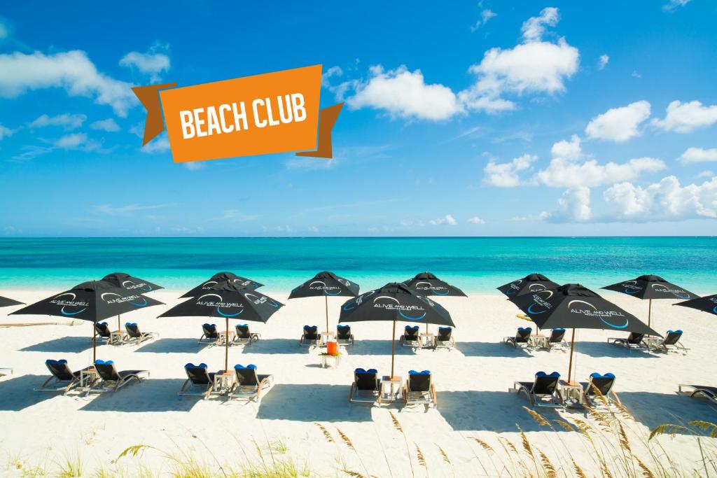 a beach with chairs and umbrellas and the ocean at One ON Marlin Resort in Turtle Cove