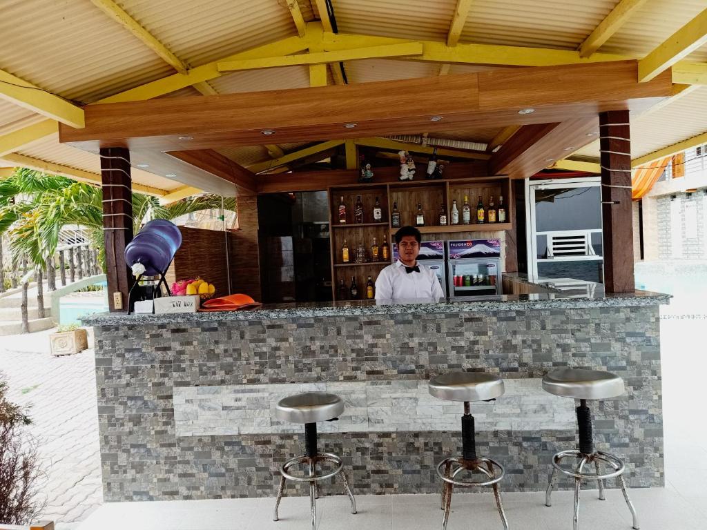 a man standing behind a bar with stools at GingGing Hotel And Resort in Oslob