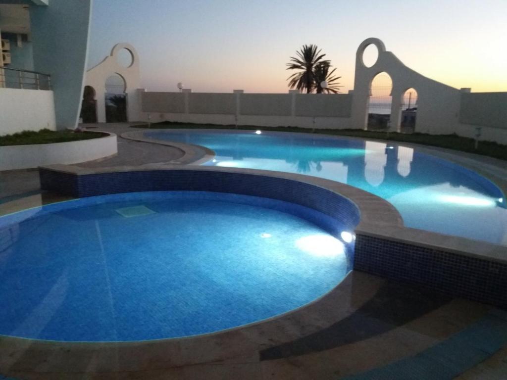 a large blue swimming pool in a building at Studio appartment beach front in Harqalah