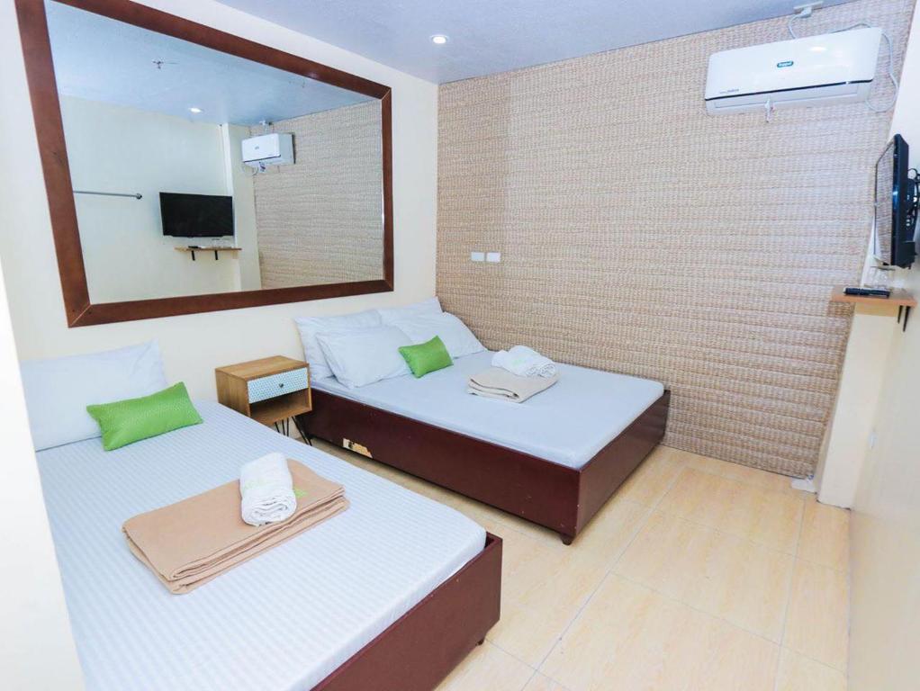 Una habitación de hotel con dos camas y un espejo. en Acs Pension House, en Koronadal