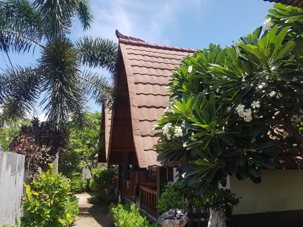 a house with palm trees in front of it at Tapada in Gili Islands