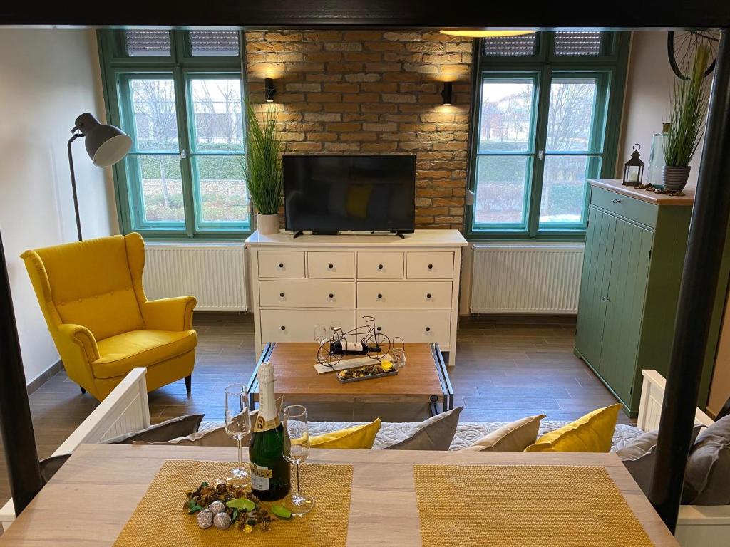 een woonkamer met een tafel en een gele stoel bij Pedal Apartman Szeged City in Szeged