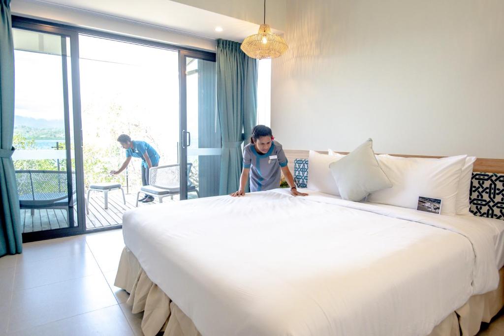 un hombre de pie junto a una cama grande en una habitación en Loloata Island Resort, en Loloata Island