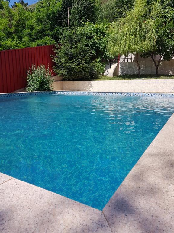 une piscine bleue avec une clôture rouge et des arbres dans l'établissement Vila Mario, à Galaţi