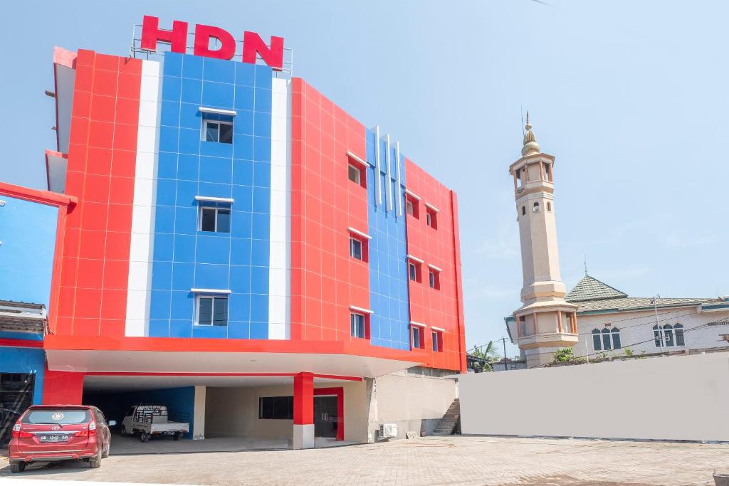 a red white and blue building with a clock tower at OYO 1633 Hotel Darma Nusantara 3 in Makassar