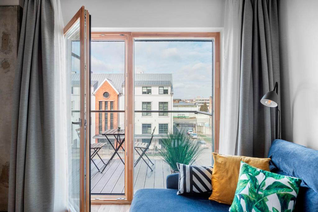 a living room with a blue couch and a large window at King Mindaugas Apartments in Kaunas