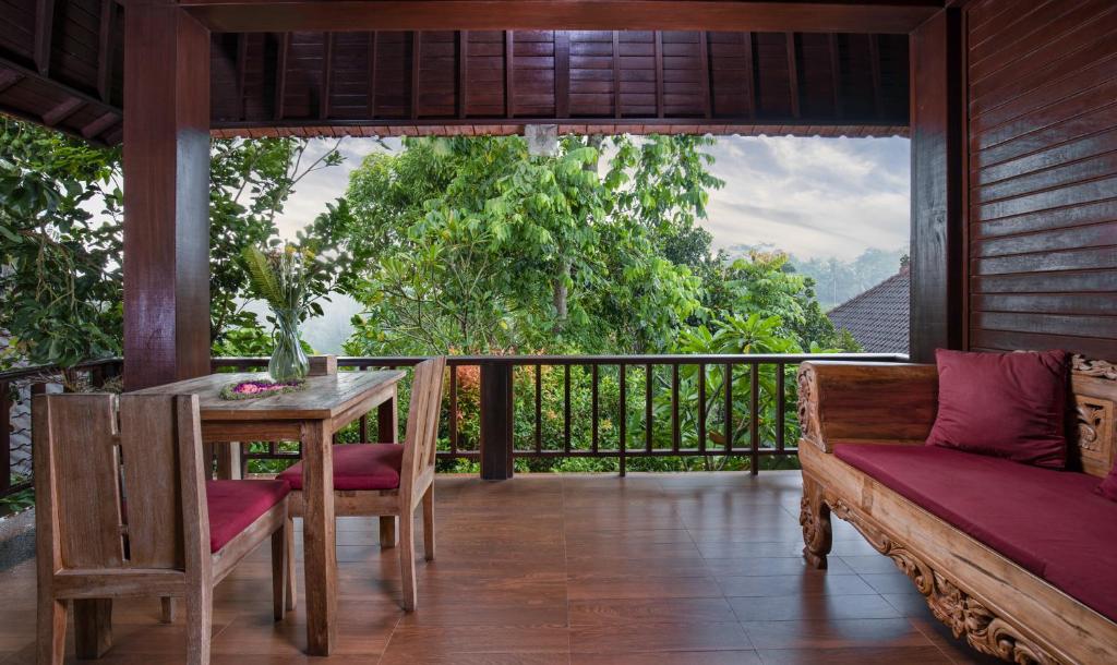 een veranda met een tafel en stoelen op een balkon bij Secluded Jungle Villa in Ubud