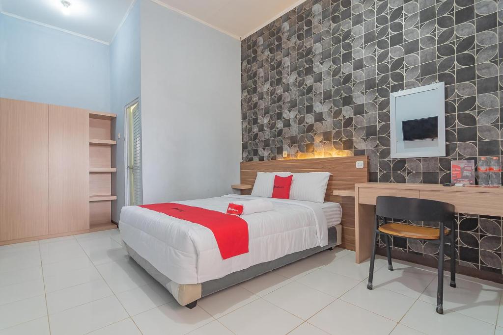 um quarto com uma cama e uma secretária com uma cadeira em RedDoorz near Alun-Alun Garut em Garut