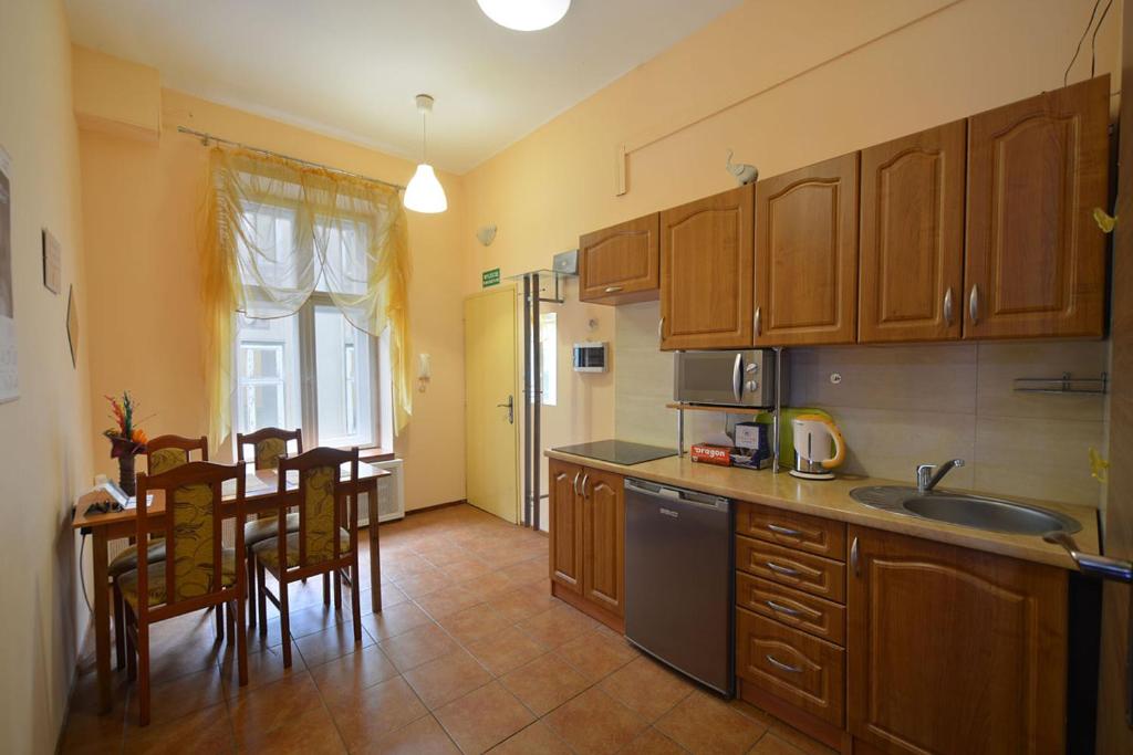 Apartaments Piotrkowska 101 في لودز: مطبخ بدولاب خشبي وطاولة مع كراسي