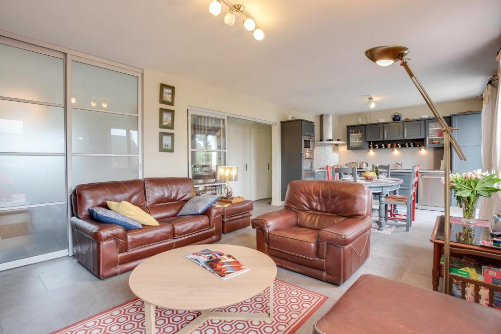 a living room with leather furniture and a table at Ti Cairn in Moëlan-sur-Mer