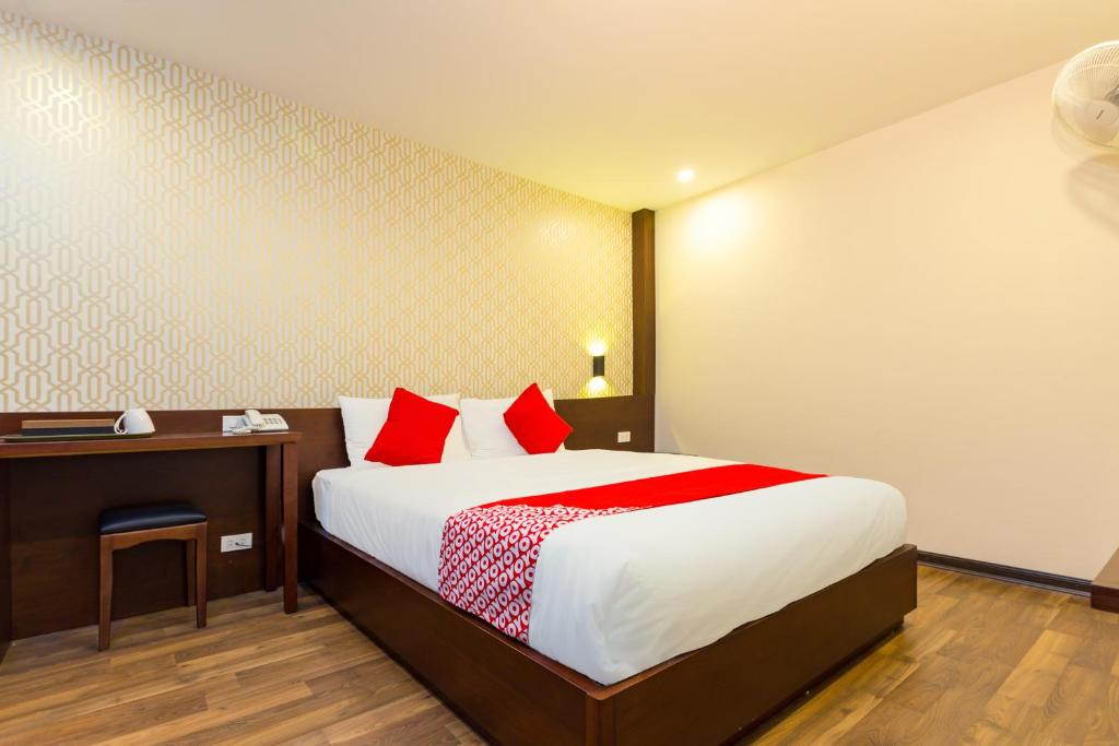 Schlafzimmer mit einem Bett mit roten Kissen und einem Schreibtisch in der Unterkunft OYO 930 Thang Long Hotel in Hanoi