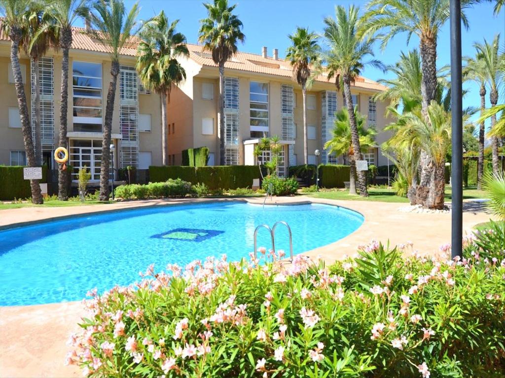 a swimming pool in front of a building with palm trees at Apartamento Golden Beach in Jávea