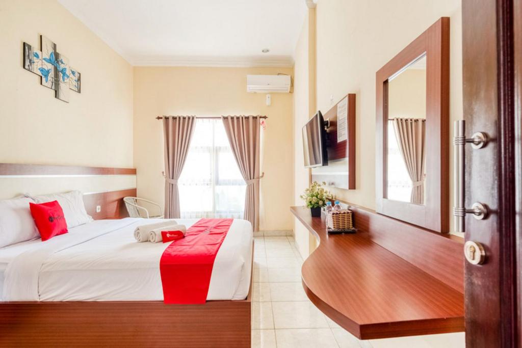 Habitación de hotel con cama y escritorio en RedDoorz Syariah @ Jalan Simpang Gajayana, en Malang