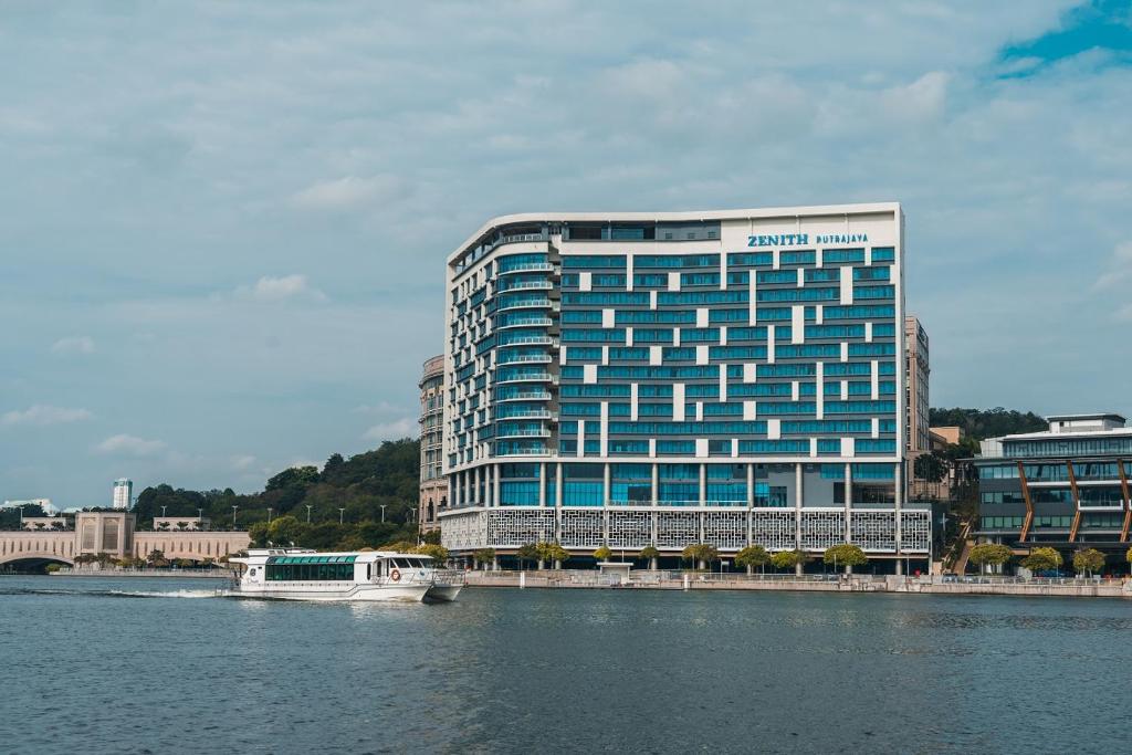 a large blue building next to a body of water at Zenith Hotel Putrajaya in Putrajaya